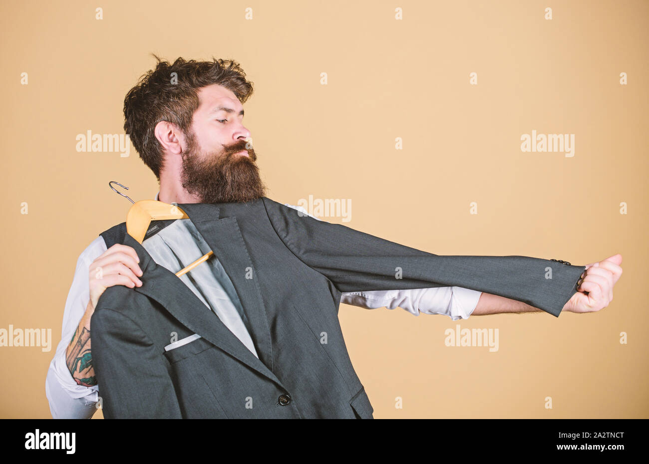 A casa su misura. Maestro sarto. Uomo Barbuto misurando la lunghezza del manicotto di tuta giacca in sartoria. Hipster holding tailor made rivestire al department store. Abbigliamento e sartoria. Foto Stock