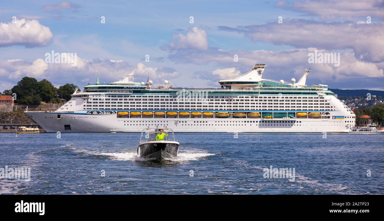 OSLO, Norvegia - piccola barca di fronte alla Explorer dei mari a Royal Caribbean Cruise nave ormeggiata presso la Fortezza di Akershus Oslo waterfront. Foto Stock