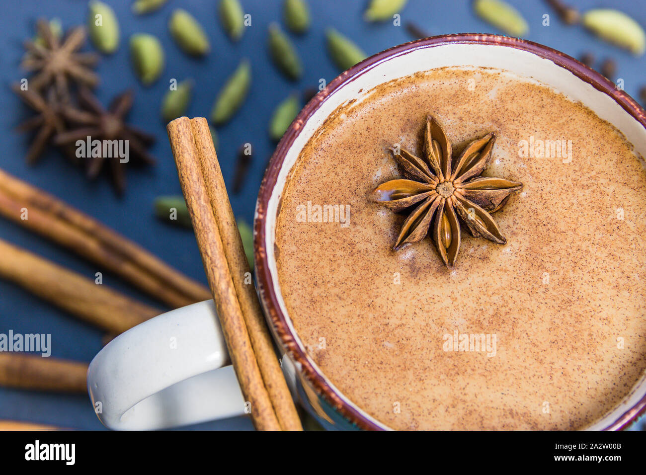 Calda tazza di tè Chai con ingredienti (anice stellato, cannella, cardamomo verde) sul tavolo Foto Stock
