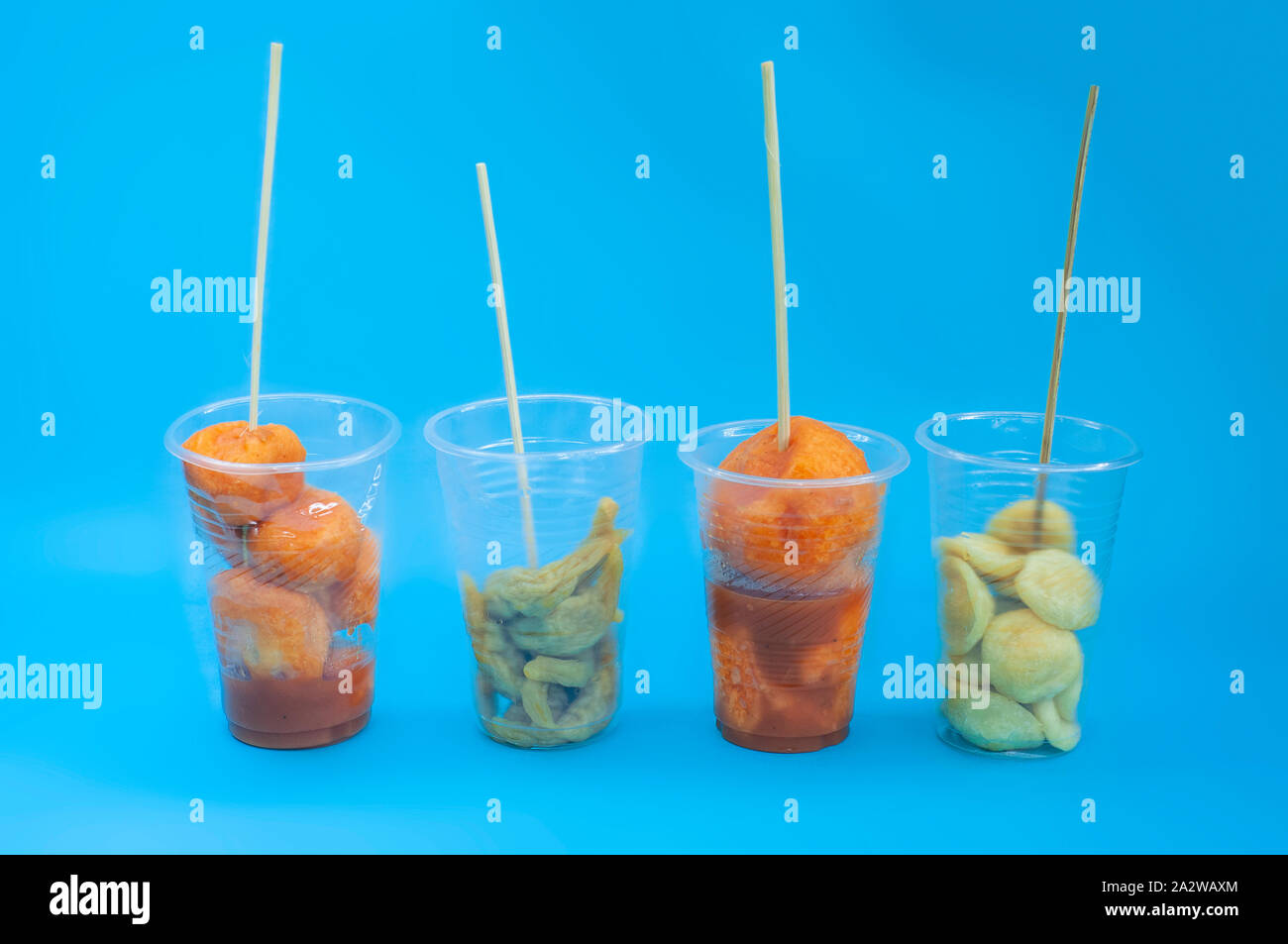 Un filippino vari cibi di strada su un bicchiere di plastica con bastoni sul blu sfondo isolato. Filippine street gli alimenti e i loro nomi come Kwek, nella - Kwek, nella Foto Stock