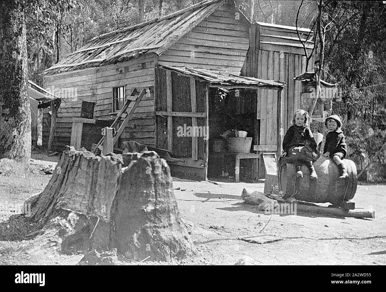 Negativo - Due bambini seduti su un barile al di fuori di una capanna Roadmenders, Mount Buffalo, Victoria, 1910, Due bambini seduti su un barile al di fuori di una capanna roadmenders Foto Stock