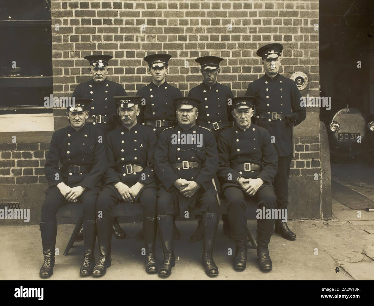 Fotografia digitale - Personale Fotografia di Williamstown Vigili del Fuoco, 1928, Personale Fotografia di Williamstown Vigili del Fuoco. Otto uomini in uniforme, quattro seduta e quattro piedi, con il muro di mattoni di Vigili del Fuoco sede dietro di loro. Questa è una foto di gruppo di Williamstown Vigili del Fuoco, 1928. Secondo la sua nipote, George Hogarty era un membro della Williamstown Vigili del Fuoco nella fine degli anni venti e primi 1930s. In seguito ha lavorato presso la Collina orientale Fire Foto Stock