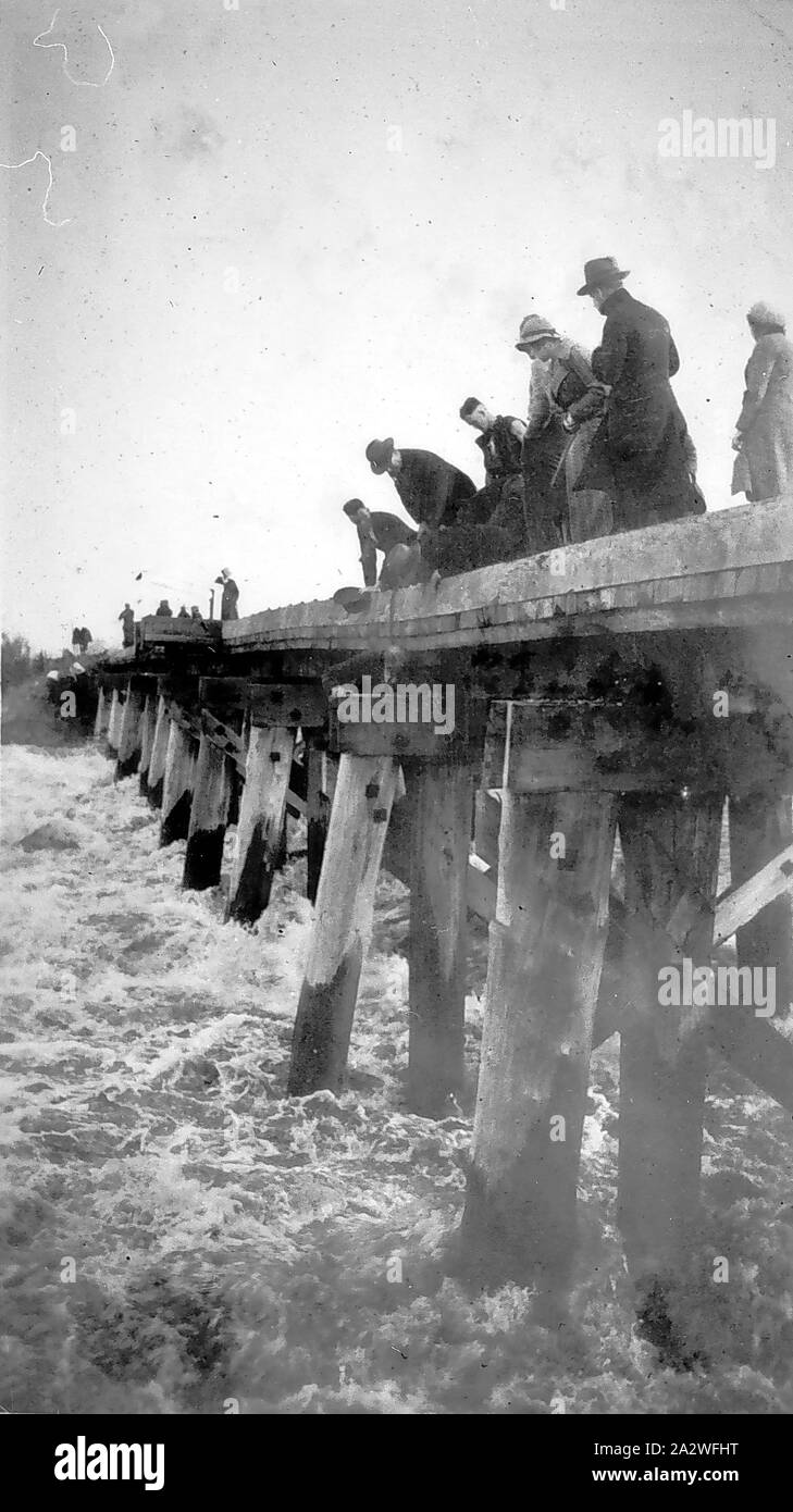 Negativo - Traralgon, Victoria, circa 1930, acque alluvionali del fiume Latrobe che scorre al di sotto del Glengarry linea rail bridge. Un certo numero di persone sono in piedi sul ponte a guardare il diluvio- acque Foto Stock