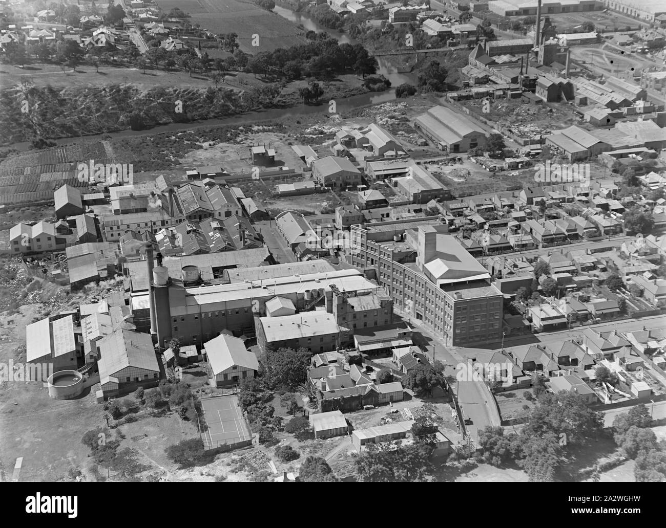 Negativo di vetro, fabbrica Vista aerea 2, Abbotsford, Victoria, circa trenta in bianco e nero, metà piastra negativa di vetro dotato di una vista aerea del Kodak Australasia Pty Ltd fabbrica a Abbotsford, circa 1930s. Questa vista obliqua guarda a sud est e mostra il multipiano edificio curvo su Southampton crescent e vari edifici in fabbrica nel centro inferiore del telaio, compreso l'argento serbatoi di recupero e campi da tennis in basso in primo piano. Nella parte superiore sinistra della Yarra Foto Stock