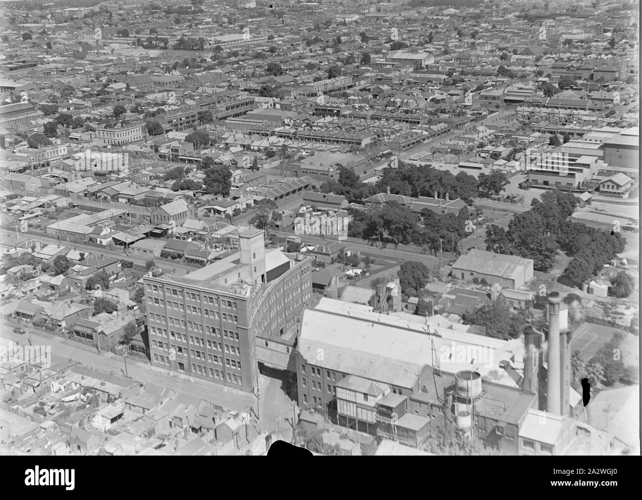 Negativo di vetro, fabbrica Vista aerea 5, Abbotsford, Victoria, circa trenta in bianco e nero, metà piastra negativa di vetro dotato di una vista aerea del Kodak Australasia Pty Ltd fabbrica a Abbotsford, circa 1930s. Questa vista obliqua guarda a nord-ovest e mostra il multipiano edificio curvo su Southampton crescent, edifici di fabbrica, camino e water tower in basso in primo piano. Al di là del complesso di fabbrica è un piccolo parco. Suburban strade e case per stiramento Foto Stock