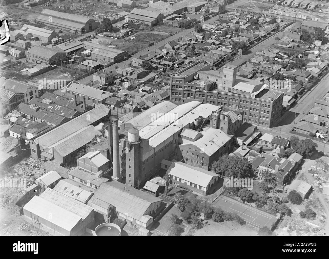 Negativo di vetro, fabbrica Vista aerea 8, Abbotsford, Victoria, circa trenta in bianco e nero, metà piastra negativa di vetro dotato di una vista aerea del Kodak Australasia Pty Ltd fabbrica a Abbotsford, circa 1930s. Questa vista obliqua è rivolta a sud e mostra il complesso di fabbrica, incluso il camino, argento recupero e serbatoi per acqua, personale di aree ricreative e curvo edificio multipiano in Southampton Crescent. Suburban strade e case sono visibili al di là. Questo è uno dei Foto Stock