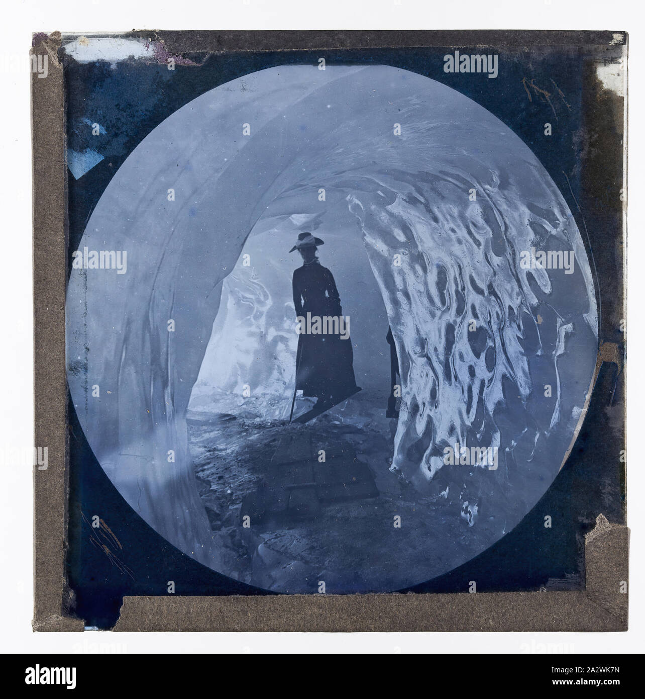 Lantern Slide - Donna nella caverna di ghiaccio, circa 1900, Lanterna della slitta di una donna attraversando una piccola crepa in una caverna di ghiaccio. Dal 1880 circa questo formato di fotografico lantern slide è venuto a dominare la diapositiva produzione. pre-apparecchiatura cinematografica e ephemera australiane e governi vittoriano nel 1975. Film e archivio sonoro della British Foto Stock