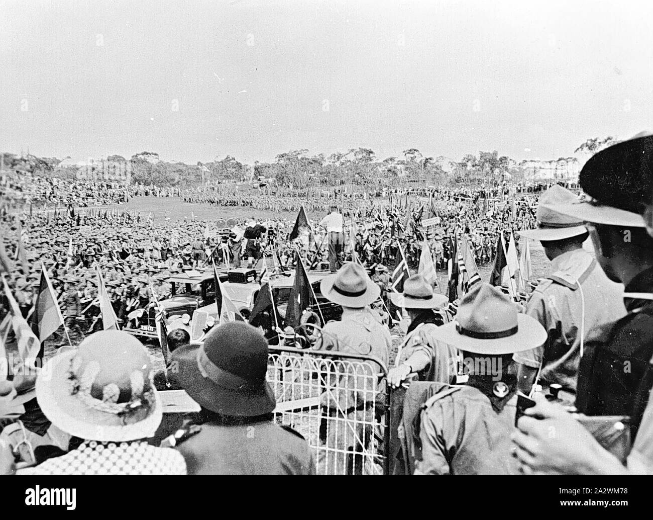 Negativo - World Scout Jamboree cerimonia, Frankston, Victoria, 1935, World Scout Jamboree cerimonia al Frankston. Gli scout sono in uniforme. Ci sono tre le vetture a motore al centro dell'immagine. Vi è un uomo con una telecamera in piedi di fronte ad un gruppo di scout Foto Stock