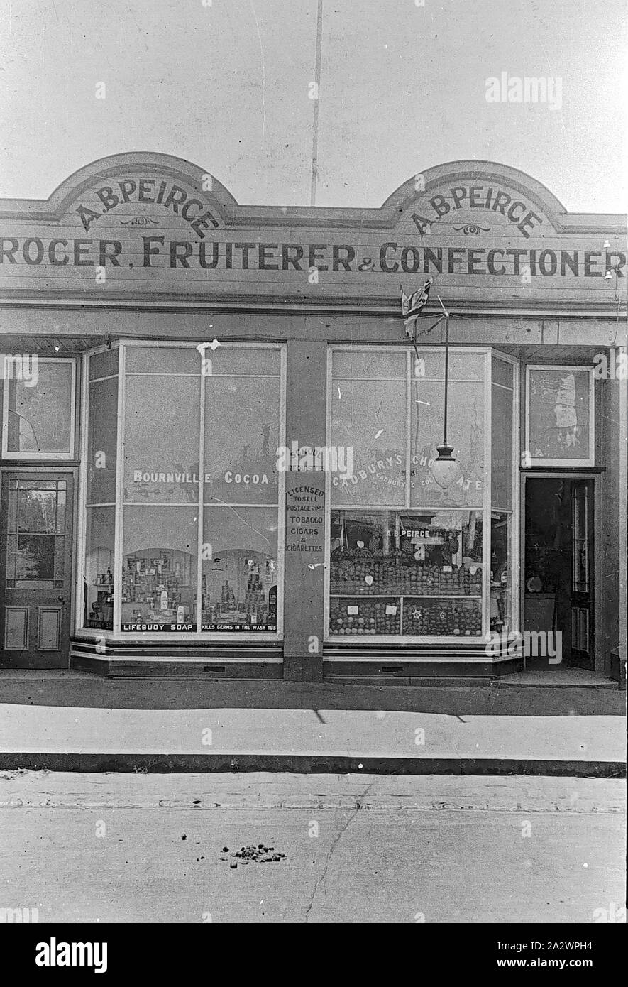 Negativo - Ballarat, Victoria, 1919, il negozio di A. B. Peirce, drogheria, Fruiterer e pasticceria. Prodotti come il 'Bournville Cocoa' e 'Cadbury cioccolato dell' sono pubblicizzati su windows del negozio Foto Stock