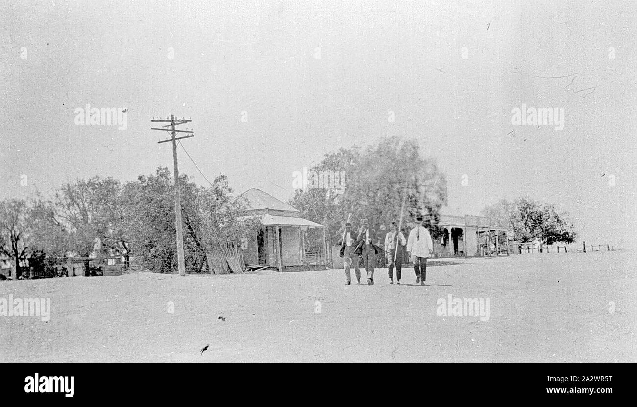 Negativo - Swan Hill District, Victoria, circa 1920, quattro uomini camminare per la strada in un paese di campagna Foto Stock