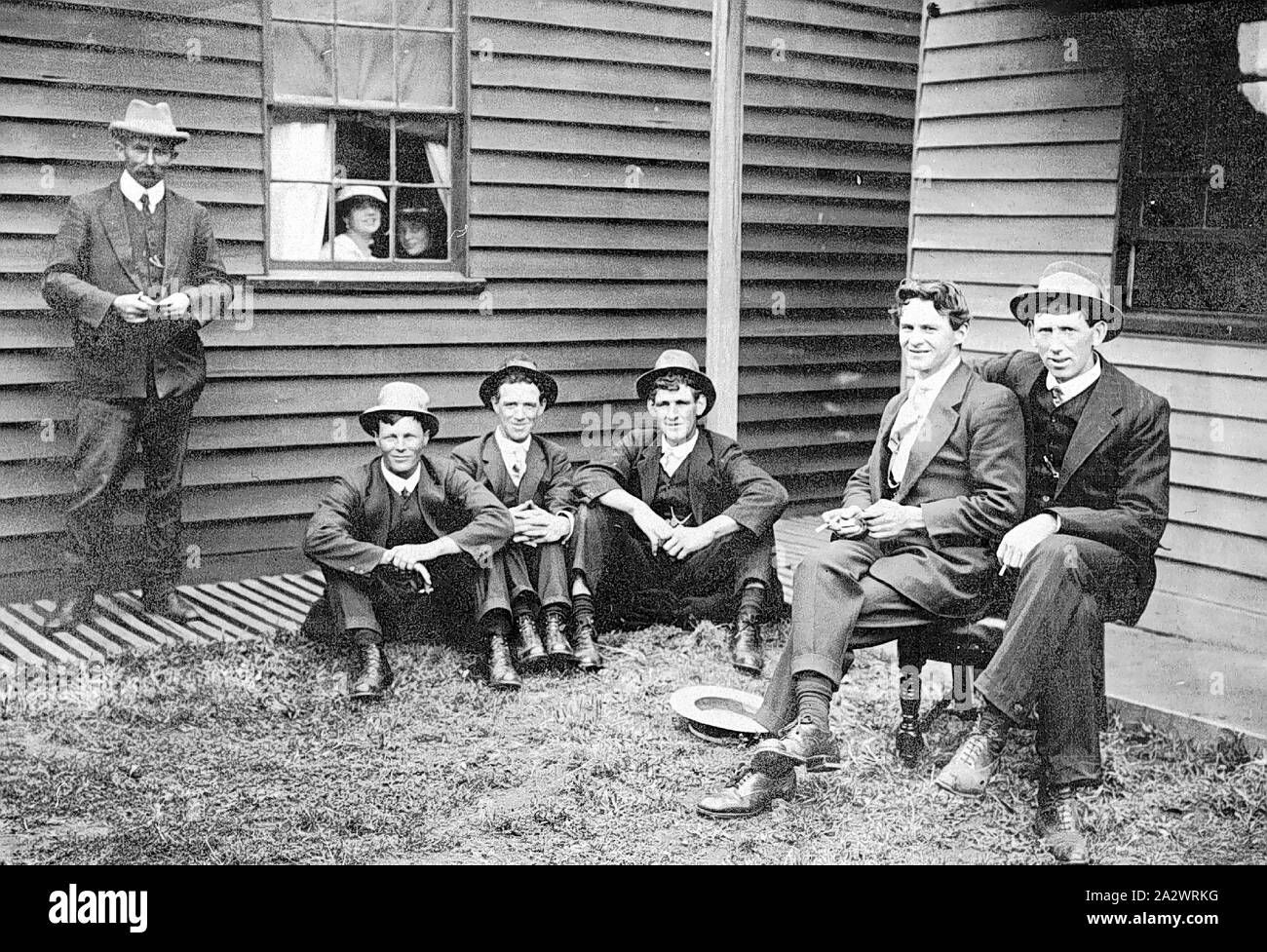 Negativo - Strathdownie, Victoria, 1920, sei uomini al di fuori del Strathdownie Hotel. Due donne peer attraverso la finestra Foto Stock