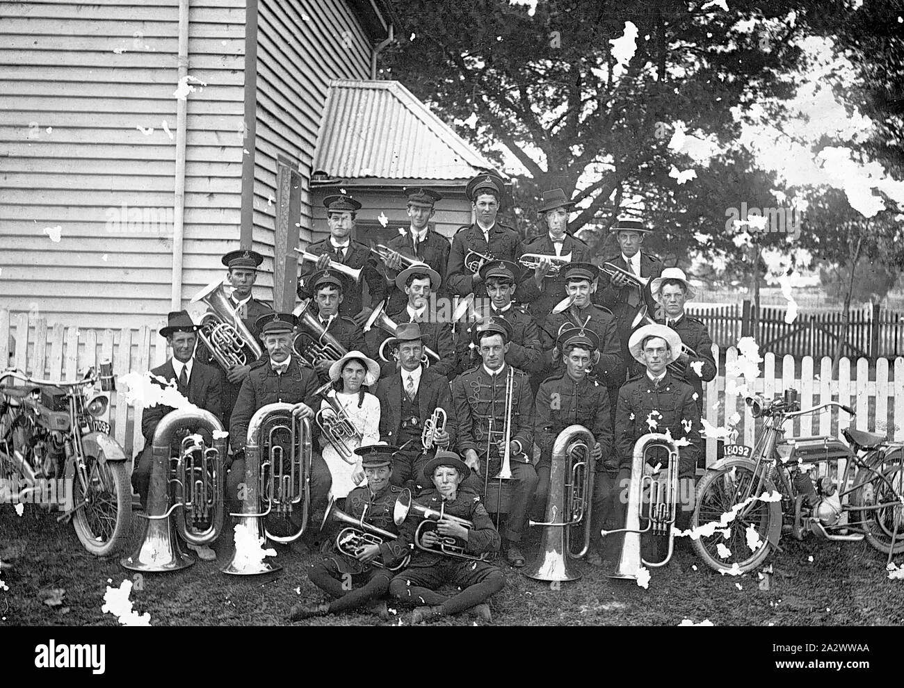 Negativo - Traralgon Brass Band, Traralgon, Victoria, 1915, Traralgon Brass Band in circa 1915. Signor Bandmaster J.T. "Tom' Tansey è seduto al centro tenendo un corno. Seduto alla sua destra (visualizzatore della sinistra) è sua figlia, Miss Hilda Tansey. Una moto è parcheggiata su ciascun lato del gruppo. Il Eufonium player, seconda bancata posteriore, estrema sinistra è Leslie C Davidson. Egli divenne grande tamburo della banda prima della sua morte nel 1960 Foto Stock