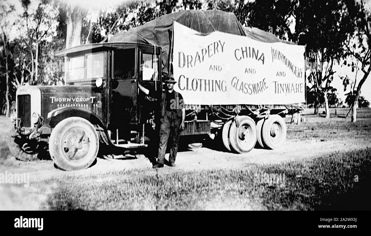 Negativo - Thornycroft carrello caricato con panneggi, Ferramenta & Homewares, Wangaratta Aeroporto District, Victoria, circa 1930, un uomo in piedi accanto a un 3-assale carrello Thornycroft. Il carrello pubblicizza: 'Drapery e abbigliamento, la Cina e la vetreria e la ferramenta e Tinware Foto Stock