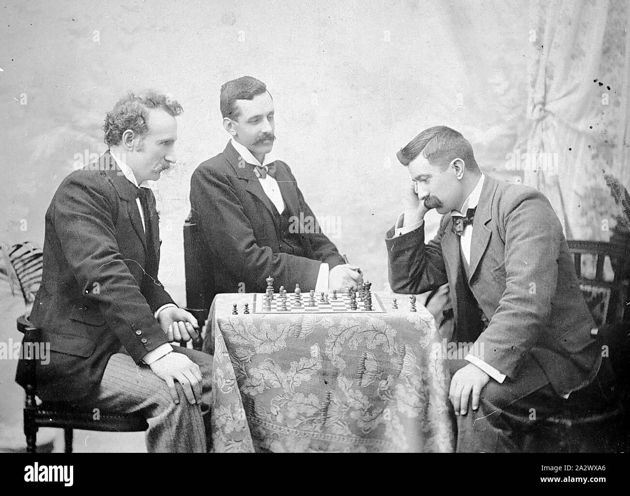 Negativo - gli uomini che giocano a scacchi, Bendigo, Victoria, 1885, due uomini giocare a scacchi con un terzo uomo a guardare Foto Stock