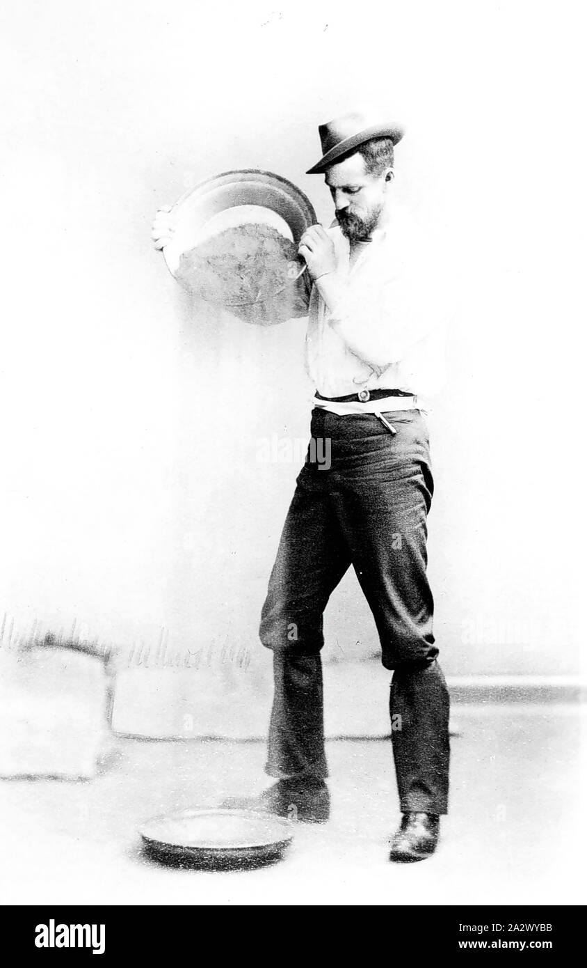 Negativo - Horsham, Victoria, circa 1904, un uomo dimostrando il panning per oro. Egli è versando il contenuto del recipiente Foto Stock