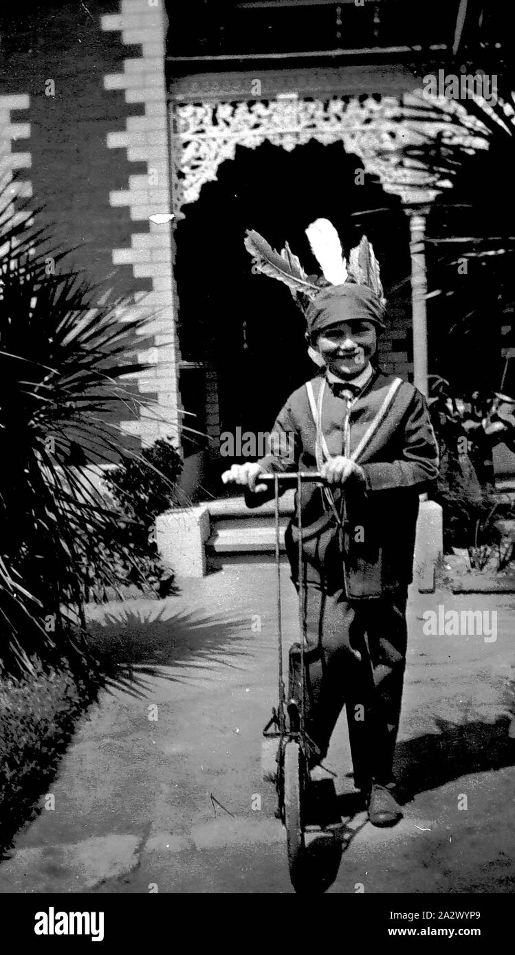 Negativo - Biancospino, Victoria, 1931, un piccolo ragazzo su uno scooter. Indossa un capo indiano vestito Foto Stock