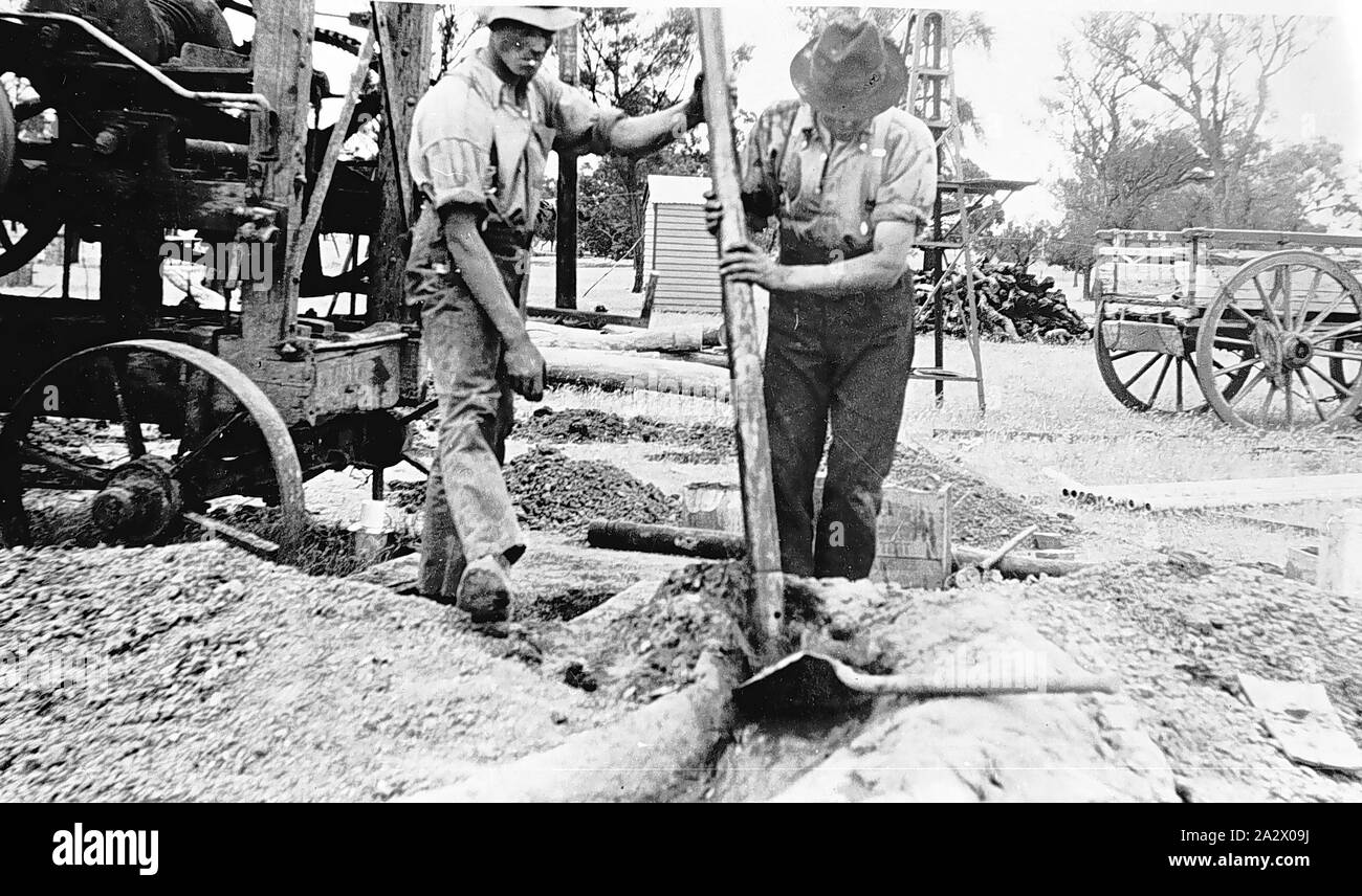 Negativo - Nhill District, Victoria, 1920, due uomini impostazione di un foro sulla fattoria Heatherlea Foto Stock