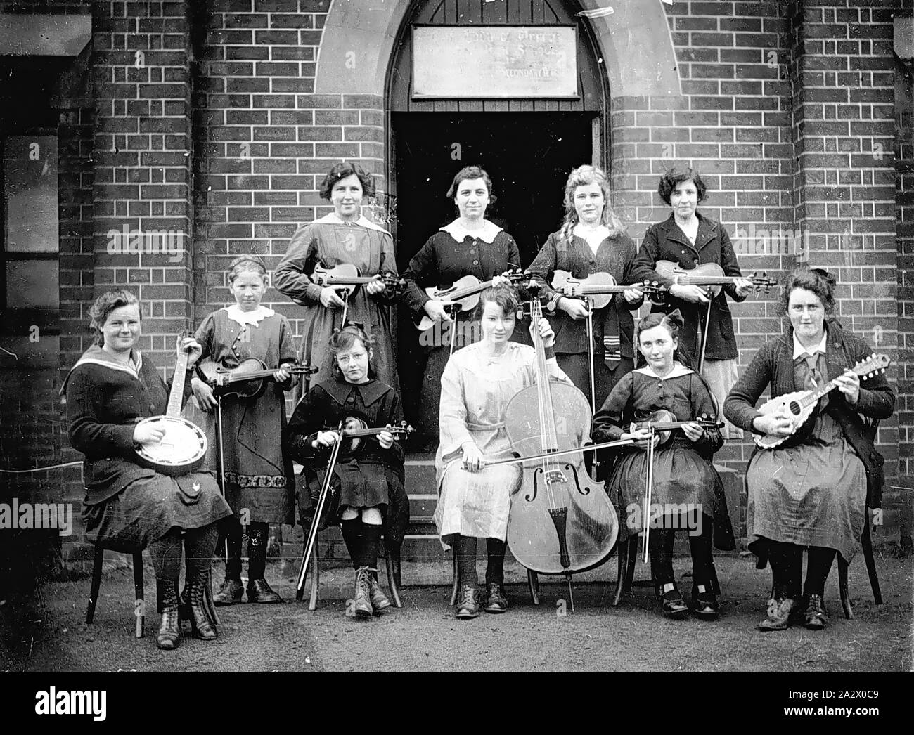 Negativo - Casterton, Victoria, 1920, un gruppo di studentesse, con i loro strumenti musicali, sui gradini del convento della misericordia. Sette ragazze di tenere i violini, uno un banjo, uno un mandolino e uno un violoncello Foto Stock