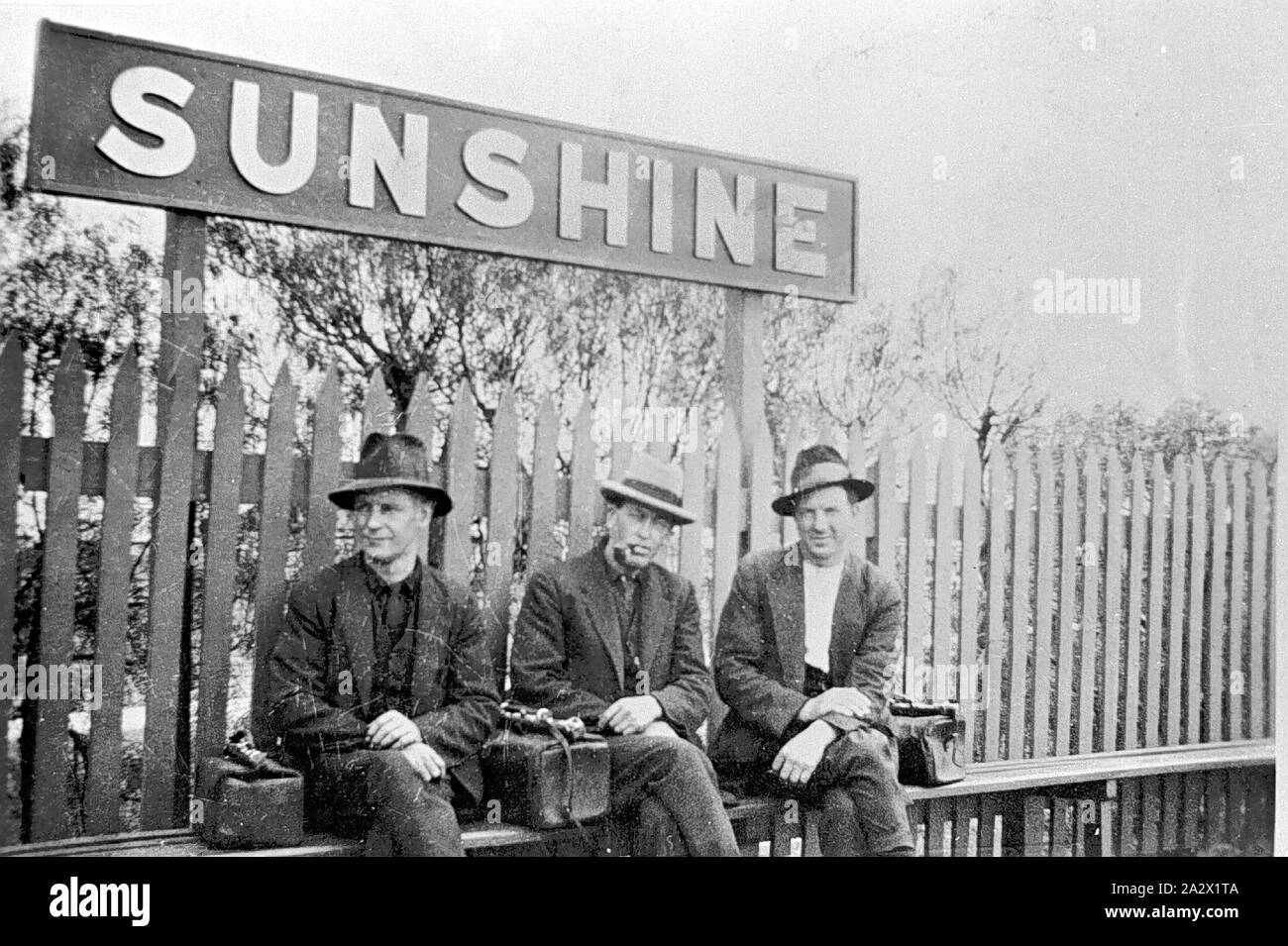Negativo - Sunshine stazione ferroviaria, 1928, fotografia in bianco e nero di tre uomini seduti al sole stazione ferroviaria nel 1928 Foto Stock