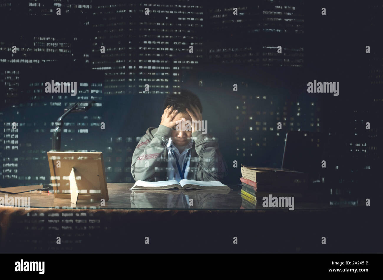 Studente maschio frustrato nello studio / cramming durante la notte per esame / Prova. Ragazzo scuola difficilmente la lettura di un libro. stanco, tabella a tarda notte preoccupati di studio Foto Stock