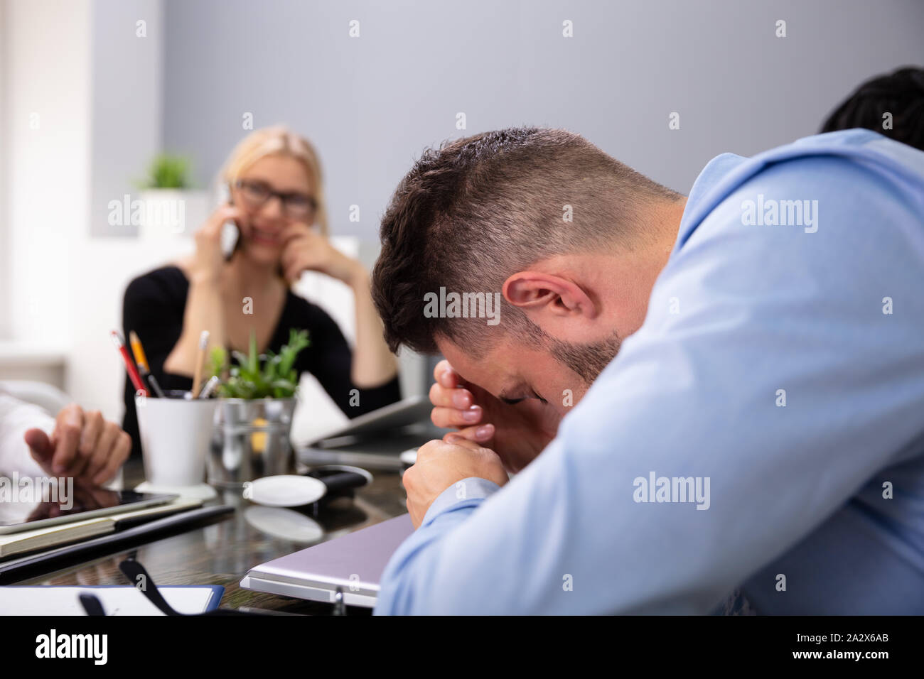 Imprenditore Getting disturbati da chiamate telefoniche del suo partner alla riunione Foto Stock