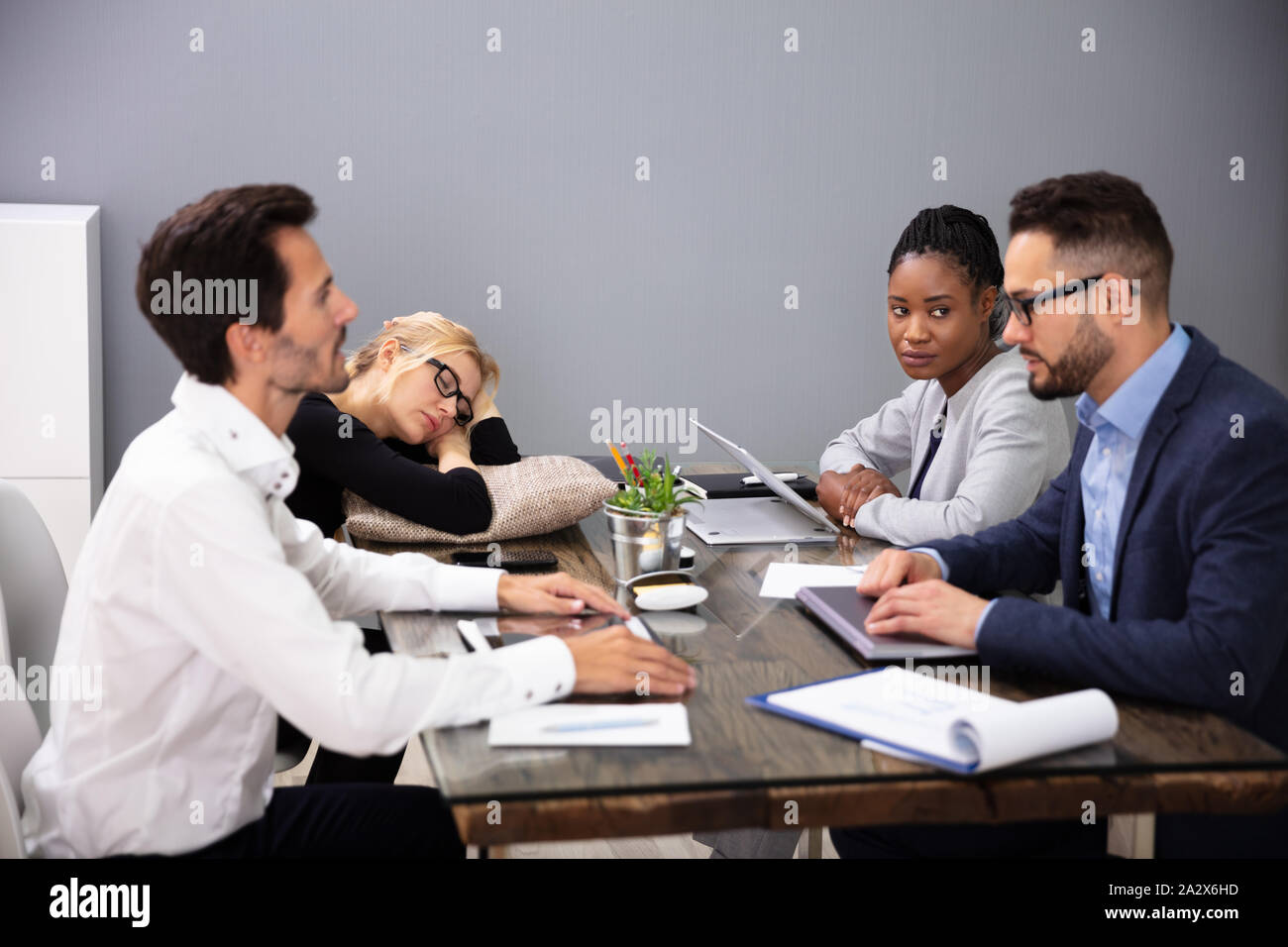 Stanco imprenditrice dormendo mentre seduto sulla scrivania in ufficio con i suoi colleghi Foto Stock