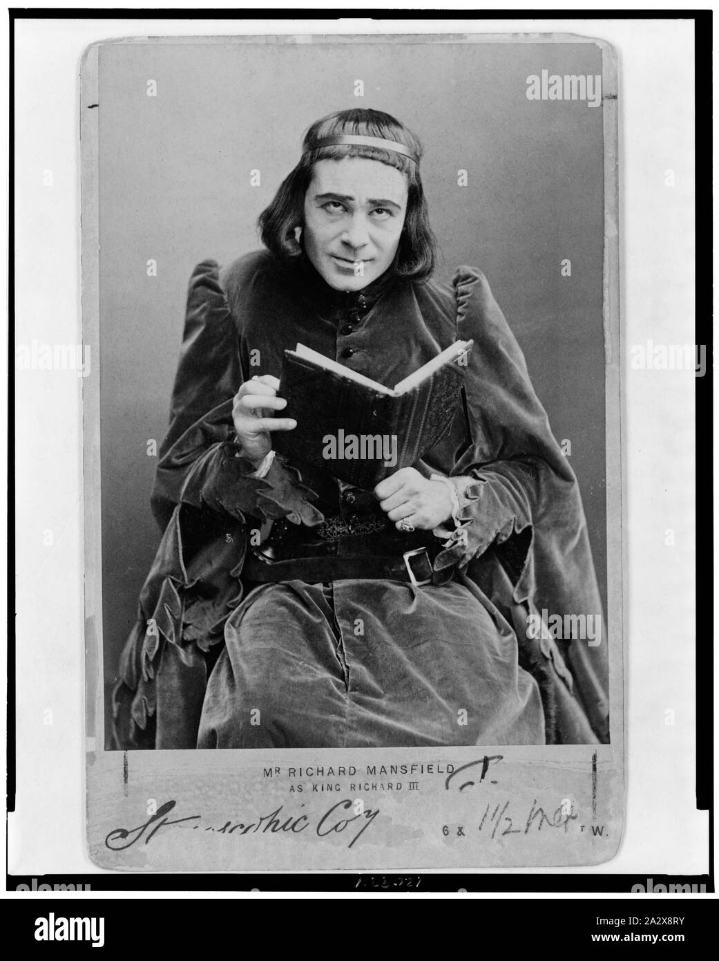 Richard Mansfield, tre quarti di lunghezza verticale, seduto, rivolto verso la parte anteriore e l'azienda prenota, come re Richard III Foto Stock