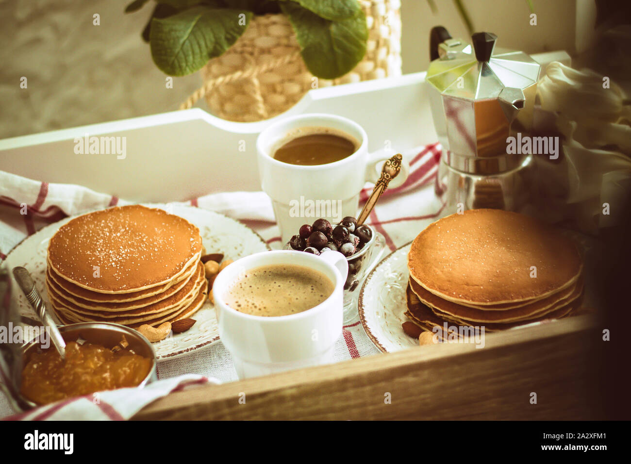 Appena in casa tradizionale colazione per due: pancake, tazze da caffè sul vassoio con panno checkred Foto Stock