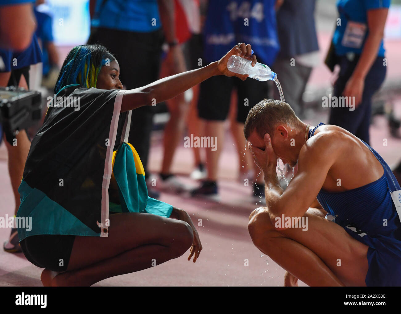 DOHA in Qatar. 03Th oct, 2019. Shaunae Miller-Uibo delle Bahama poveri l'acqua al suo marito Maicel Uibo di Estonia dopo la concorrenza Donne 400m Finale e Mens 800M Decathlon durante il giorno 7 della IAAF mondiale di atletica - Doha 2019 Al Khalifa International Stadium il Giovedi, Ottobre 03, 2019 a Doha, in Qatar. Credito: Taka G Wu/Alamy Live News Foto Stock