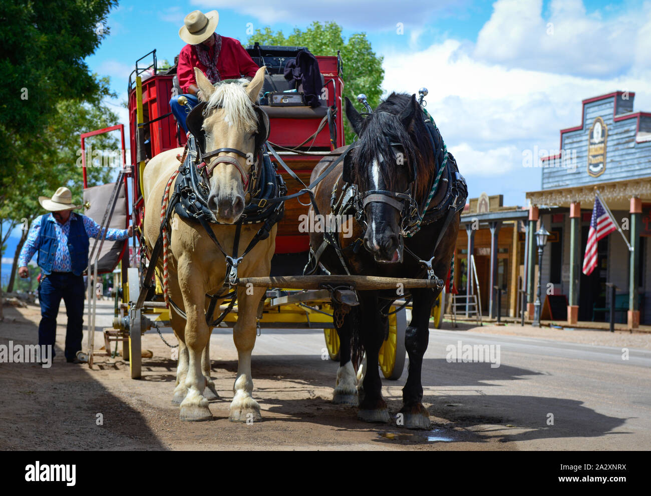 Un rosso stagecoach attende i passeggeri con due cavalli a riposo e cowboy in lapide storica, AZ, Stati Uniti d'America Foto Stock