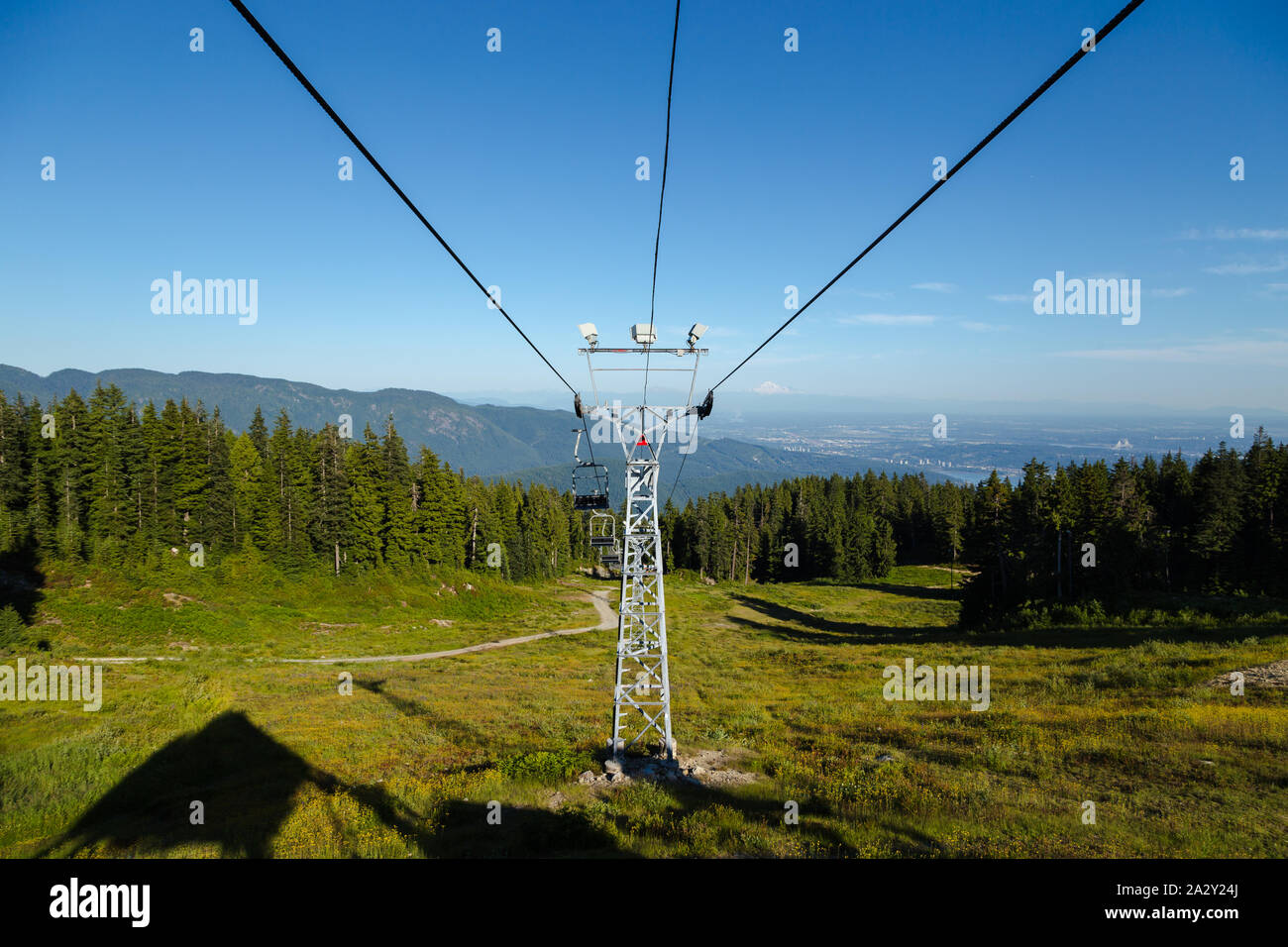 Lo ski lift accanto alla pista da sci sentiero escursionistico nella parte superiore di Seymour Mountain in North Vancouver, BC, con una vista del Fraser Valley e Mt. Baker in Foto Stock