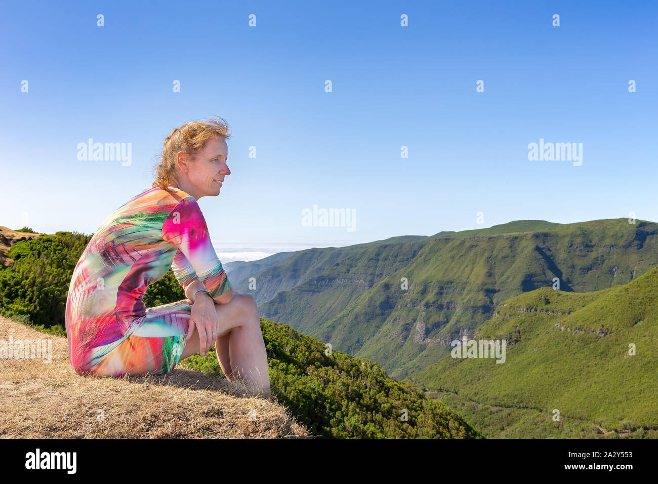 La donna caucasica si siede sulla montagna portoghese vicino a valle verde Foto Stock