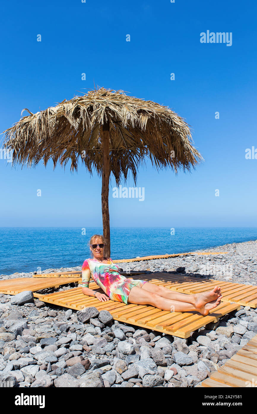 Dutch donna di mezza età a prendere il sole come turista sulla spiaggia sassosa a isola di Madera Foto Stock
