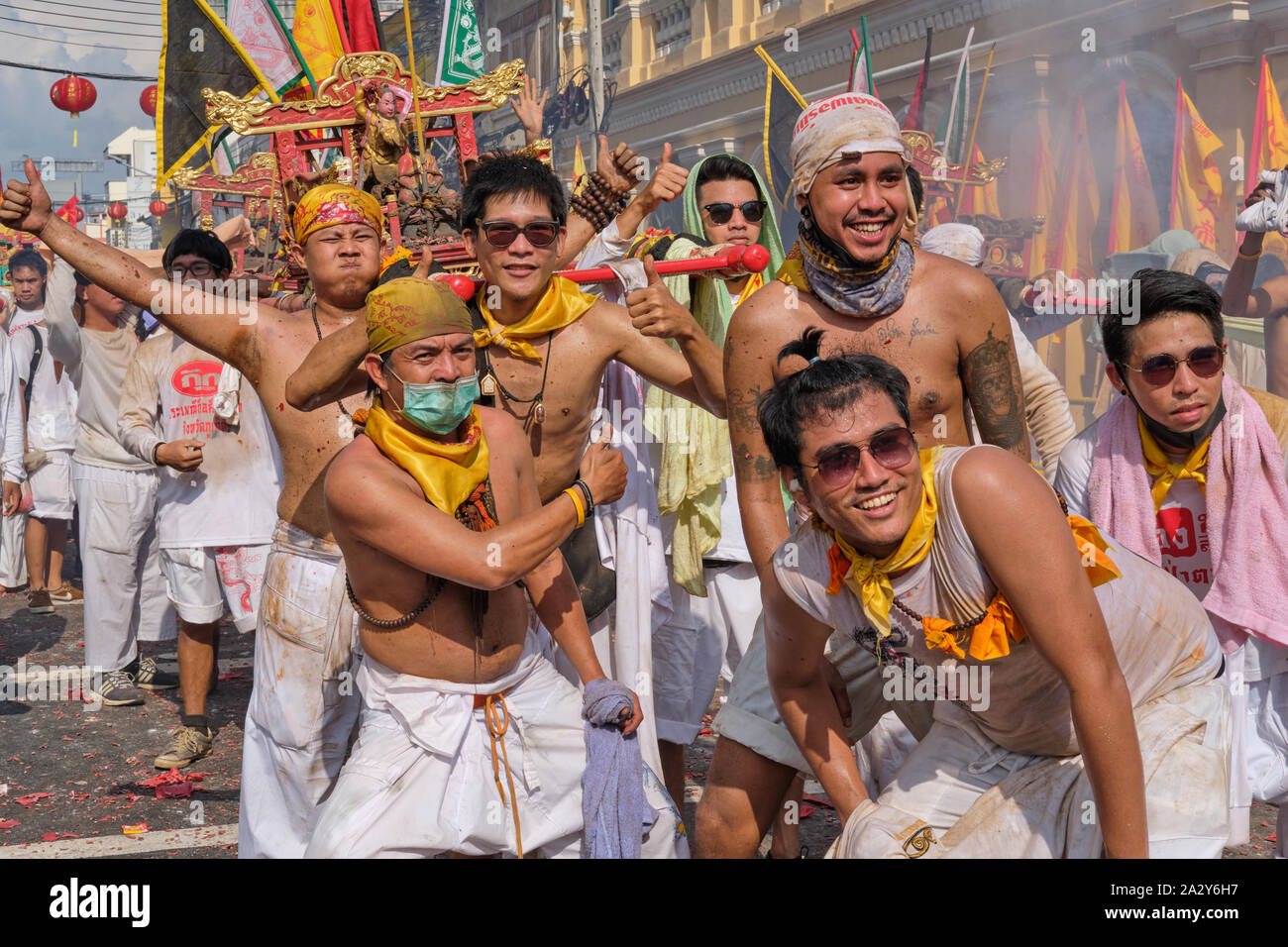 Una processione durante il Festival vegetariano nella città di Phuket, in Thailandia, con portatori di palanchini che portano statue di divinità cinesi in posa per le foto Foto Stock