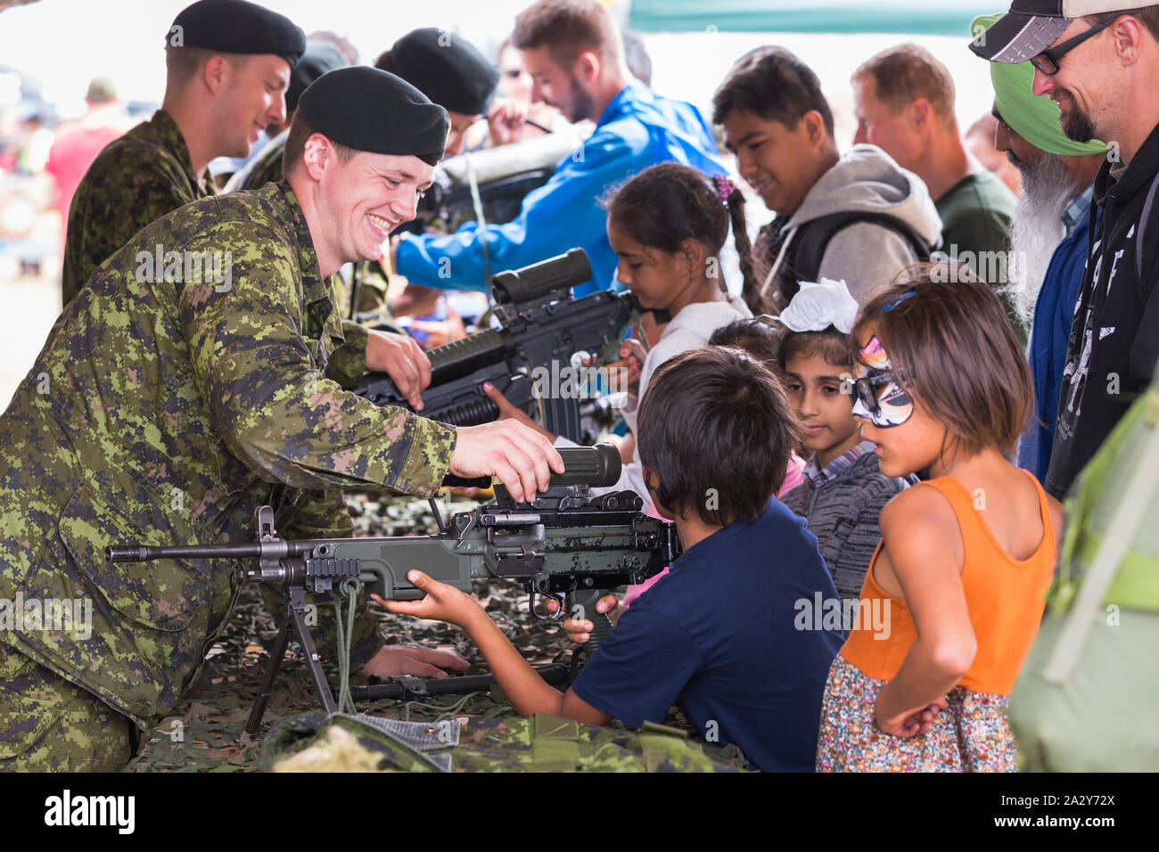 ABBOTSFORD, BC, CANADA - 11 AGOSTO 2019: Un soldato delle forze armate canadesi che mostra ai bambini un fucile automatico all'Abbotsford International Airshow. Foto Stock