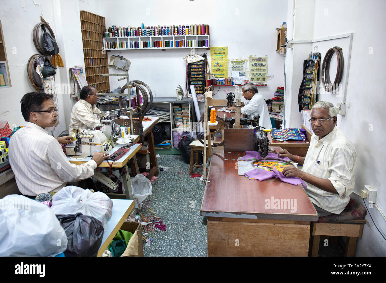 Sarti nel loro negozio seduti davanti a una macchina da cucire, rendendo bellissimi disegni in Muscat Oman. Foto Stock