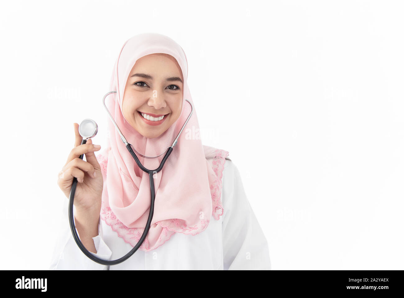 Ritratto di una giovane e bella donna musulmana medico indossa uno stetoscopio e permanente sorriso in una camera di esame presso l'ospedale su sfondo bianco. Foto Stock