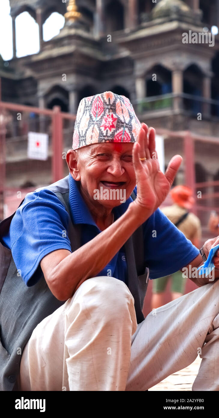 Un vecchio uomo nepalese con la faccia felice guardando la telecamera mentre posa a Patand Durbar Square Foto Stock
