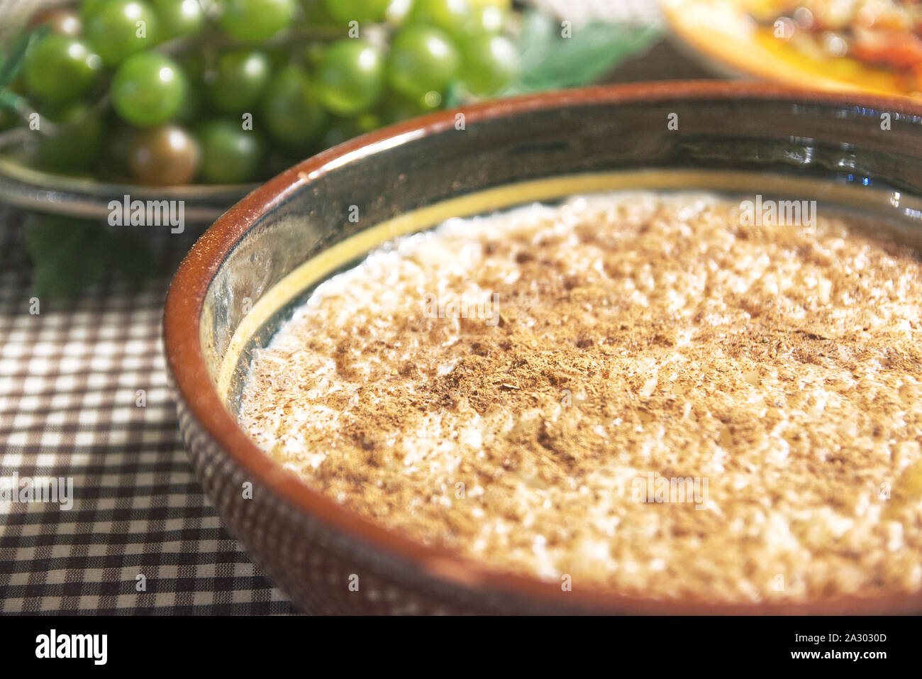 Tipico spagnolo Arroz con leche, budino di riso su un tavolo ricoperto da una tovaglia servita con alcuni frutti e in una cucina rustica. Copia vuota dello spazio. Foto Stock