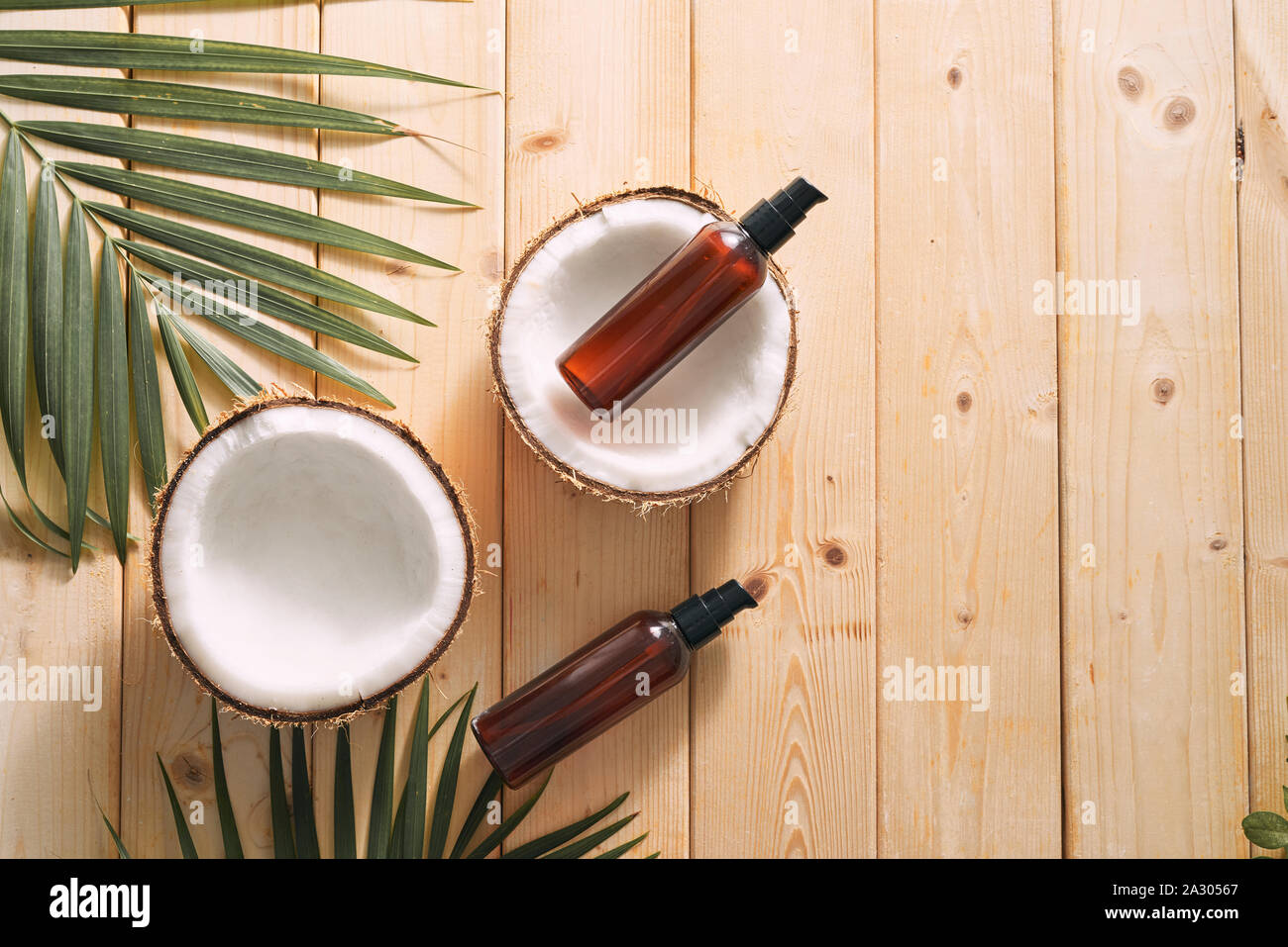 Foglia tropicale, cura i cosmetici e noce di cocco su un tavolo di legno. Vista dall'alto. Mezzi per capelli, corpo, pelle. flatlay Foto Stock