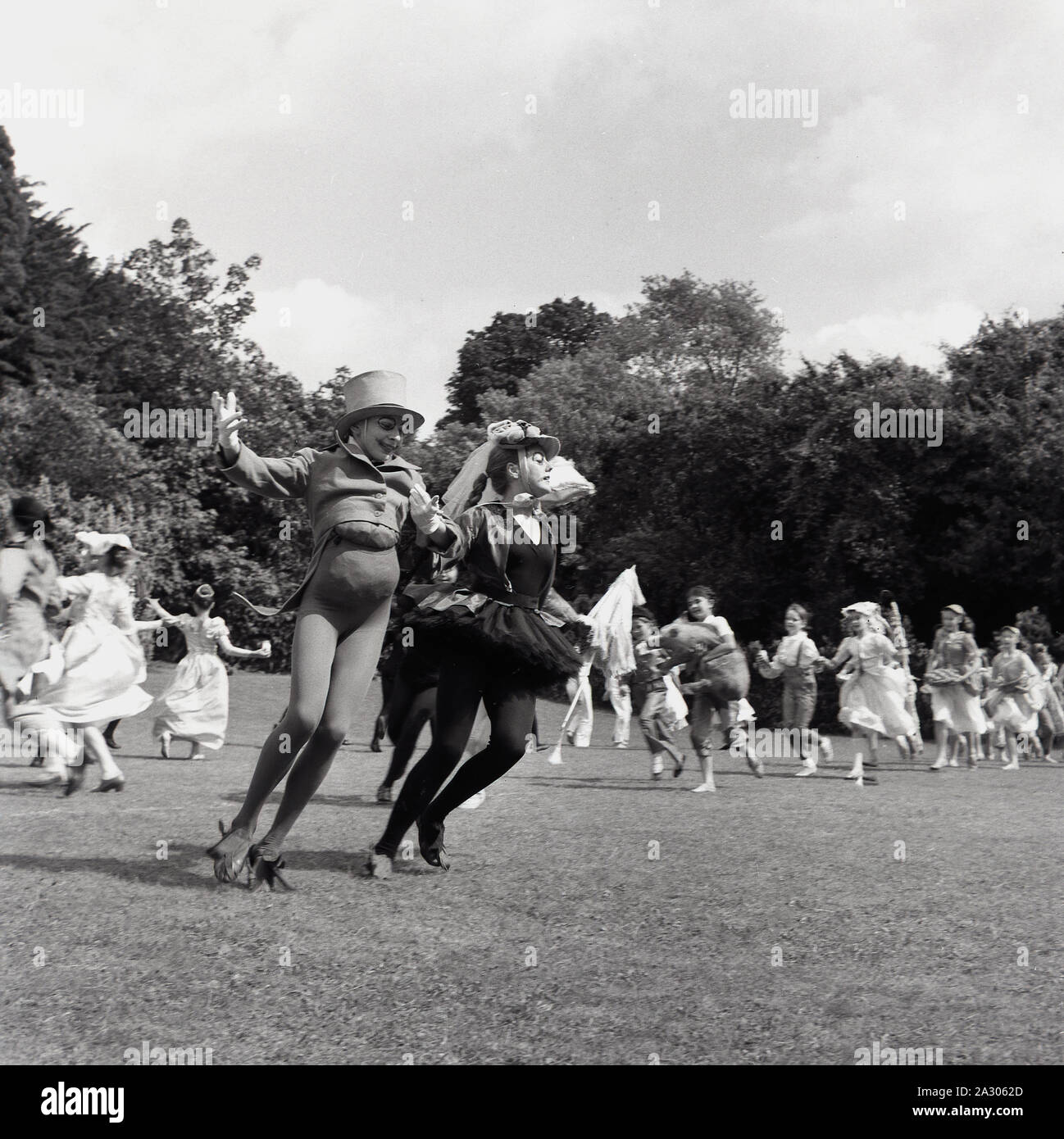 Anni '1960, storico, arte Tring, studentesse in costumi dei personaggi di "Alice nel paese delle meraviglie" esibendosi all'esterno, Tring, Inghilterra, Regno Unito. Foto Stock