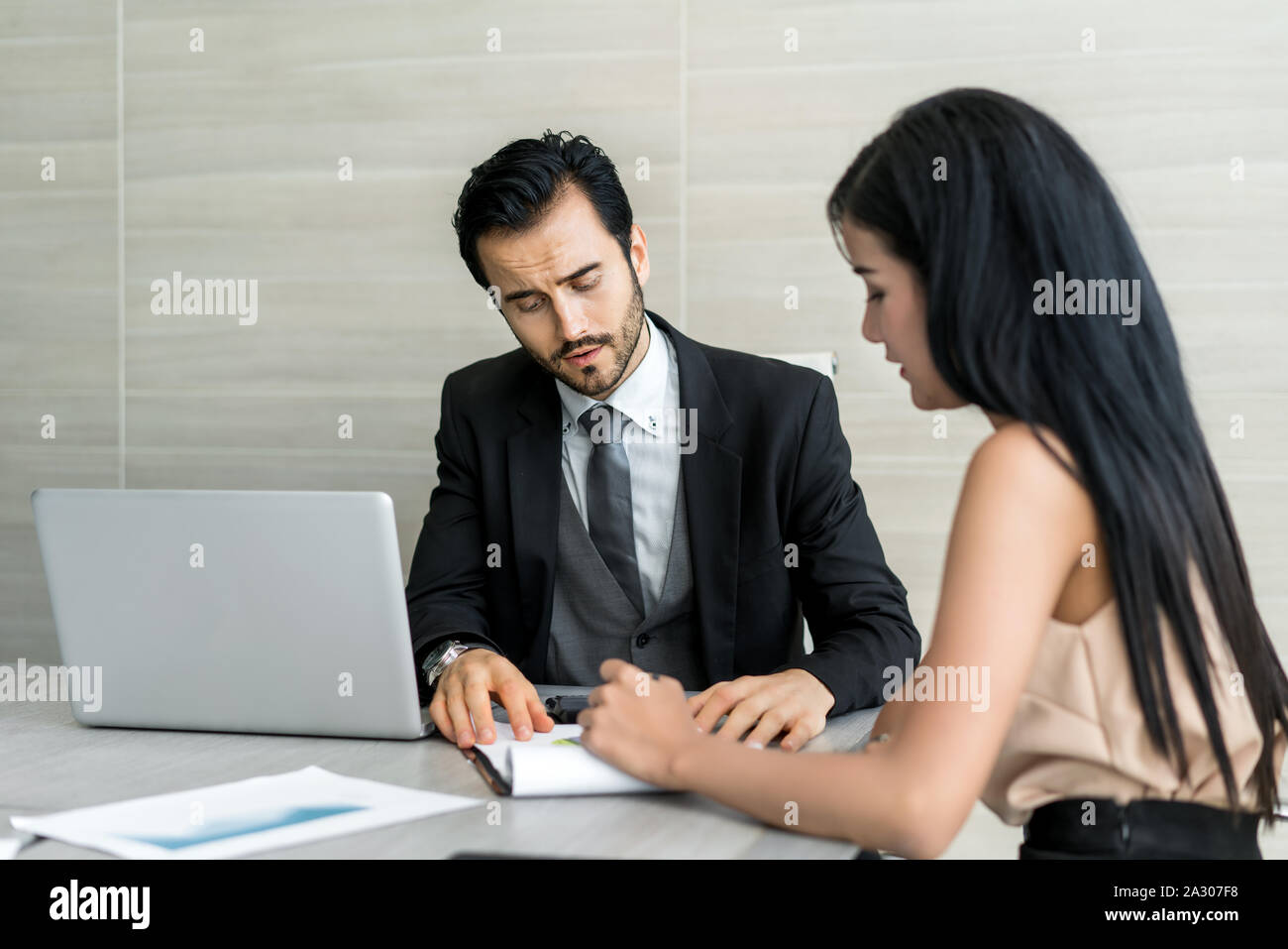 Coppia di giovani uomini di affari che lavora in un ufficio moderno, due colleghi a discutere di progetto, piccola squadra di imprenditori sorridente e guardando insieme Foto Stock