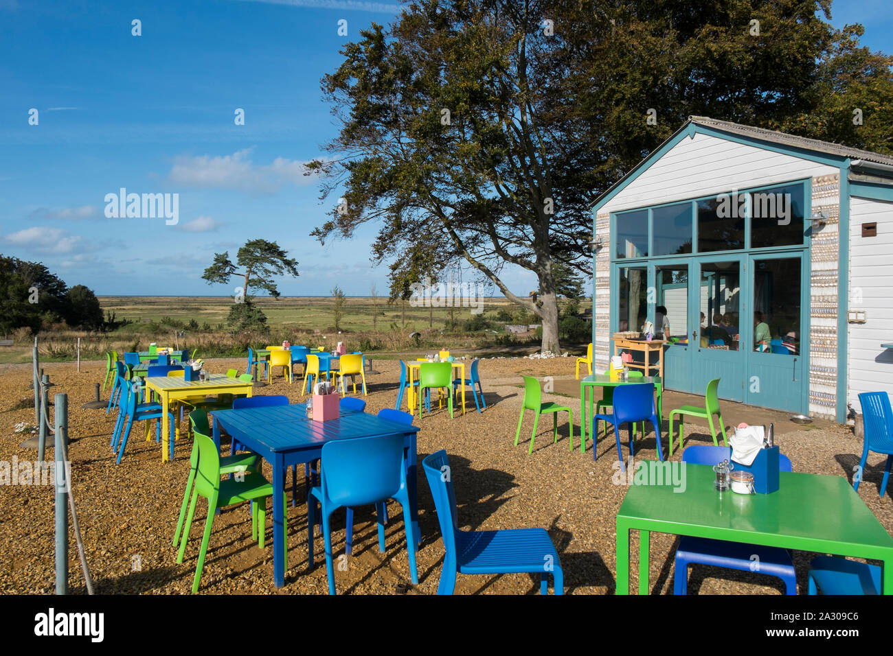 Blu, verde e giallo e i tavoli e le sedie fuori Wiveton Hall cafe, Wiveton, North Norfolk, Regno Unito Foto Stock