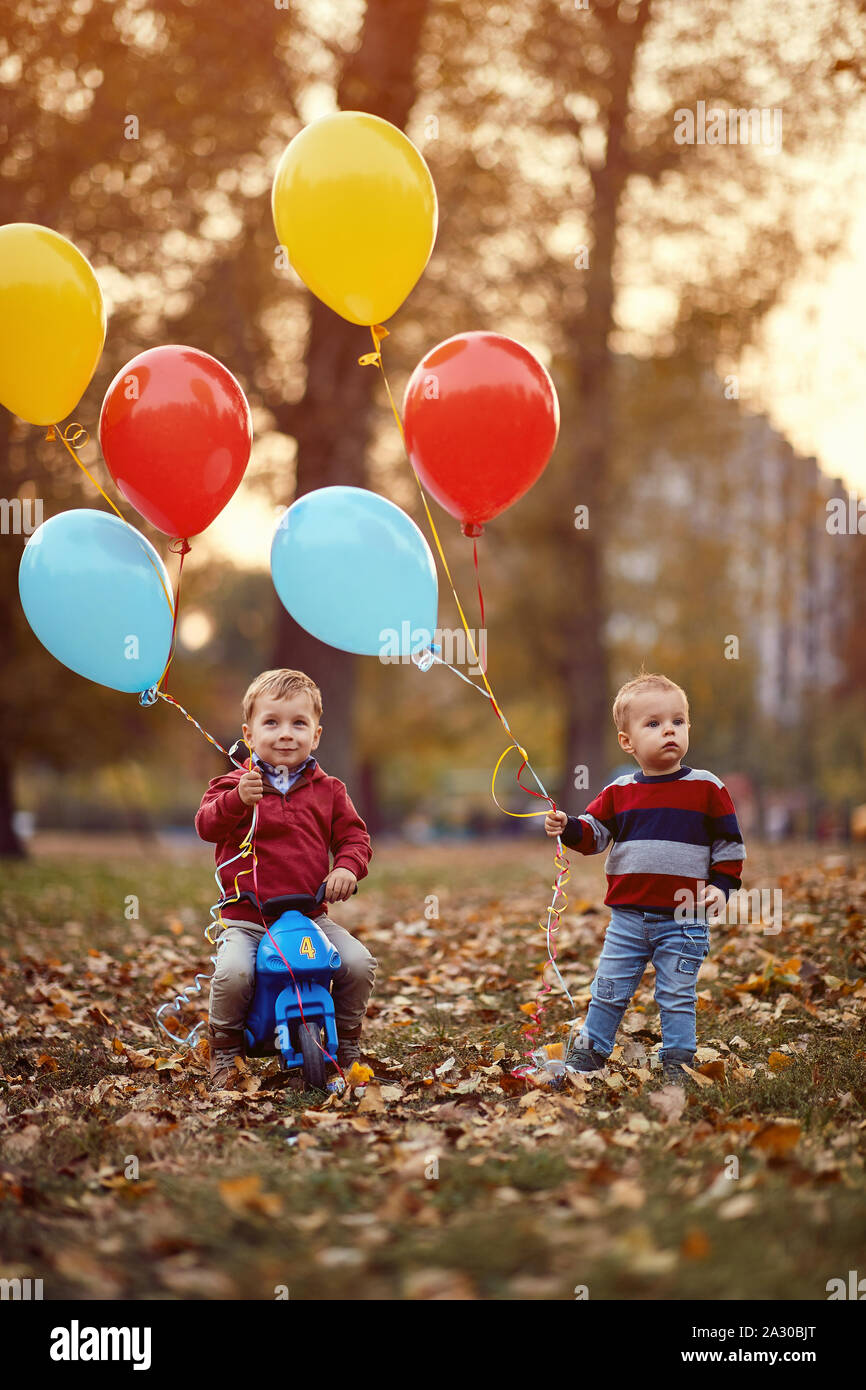 Bambino fratelli passeggiata nel parco di autunno con palloncini Foto Stock