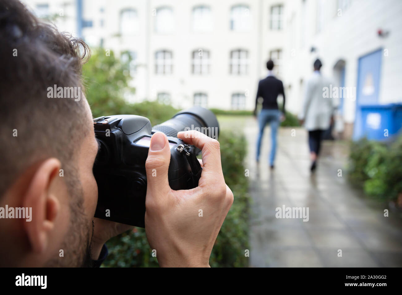 Giovane uomo Paparazzi fotografo scatta una foto con sospetto del giovane camminare insieme utilizzando una fotocamera Foto Stock