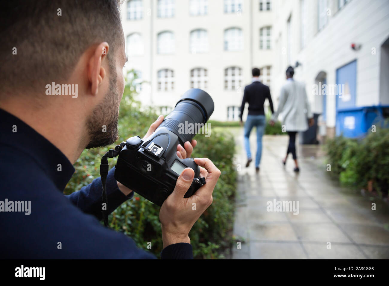 Giovane uomo Paparazzi fotografo scatta una foto con sospetto del giovane camminare insieme utilizzando una fotocamera Foto Stock