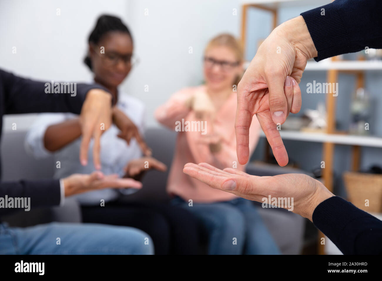 Un gruppo di più persone di etnia comunicante con la mano la lingua dei segni a casa Foto Stock