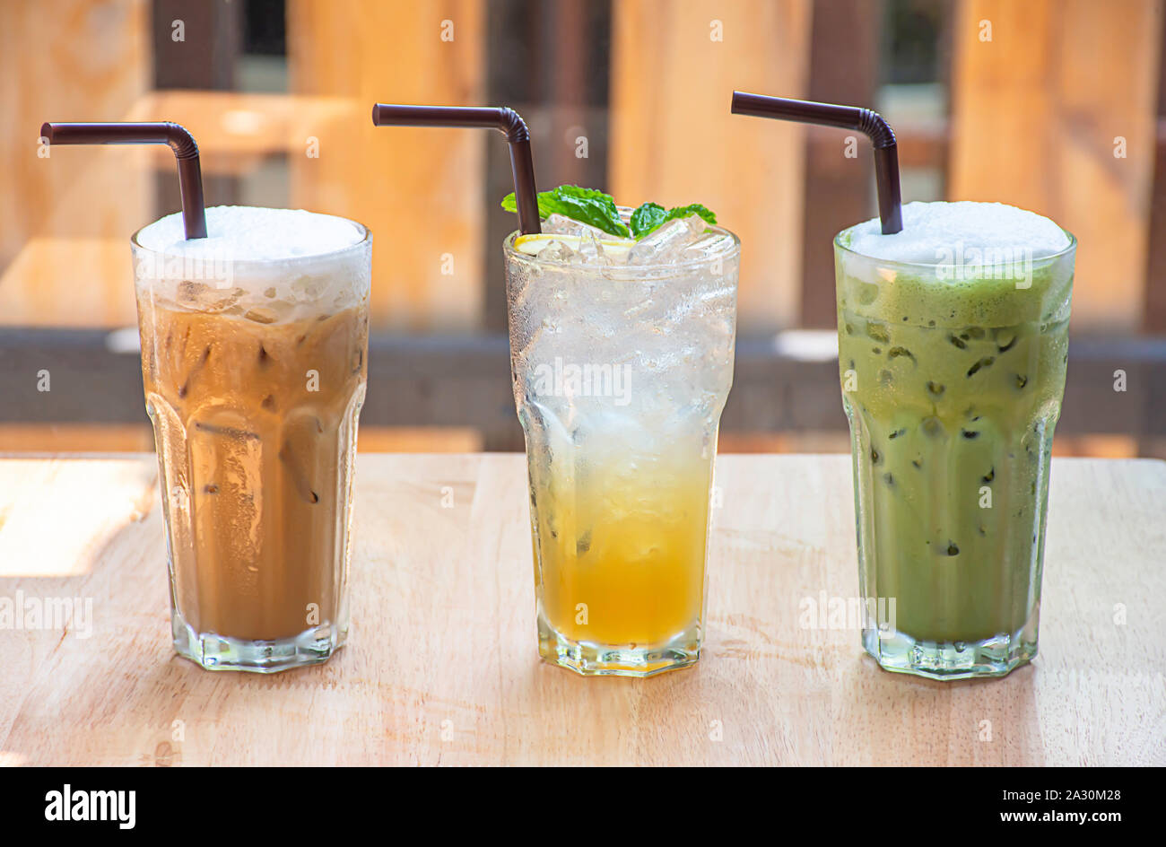 Caffè ghiacciato, miele di limone e soda frullato fragole in vetro sul tavolo di legno sfondo finestre di vetro e l'albero. Foto Stock