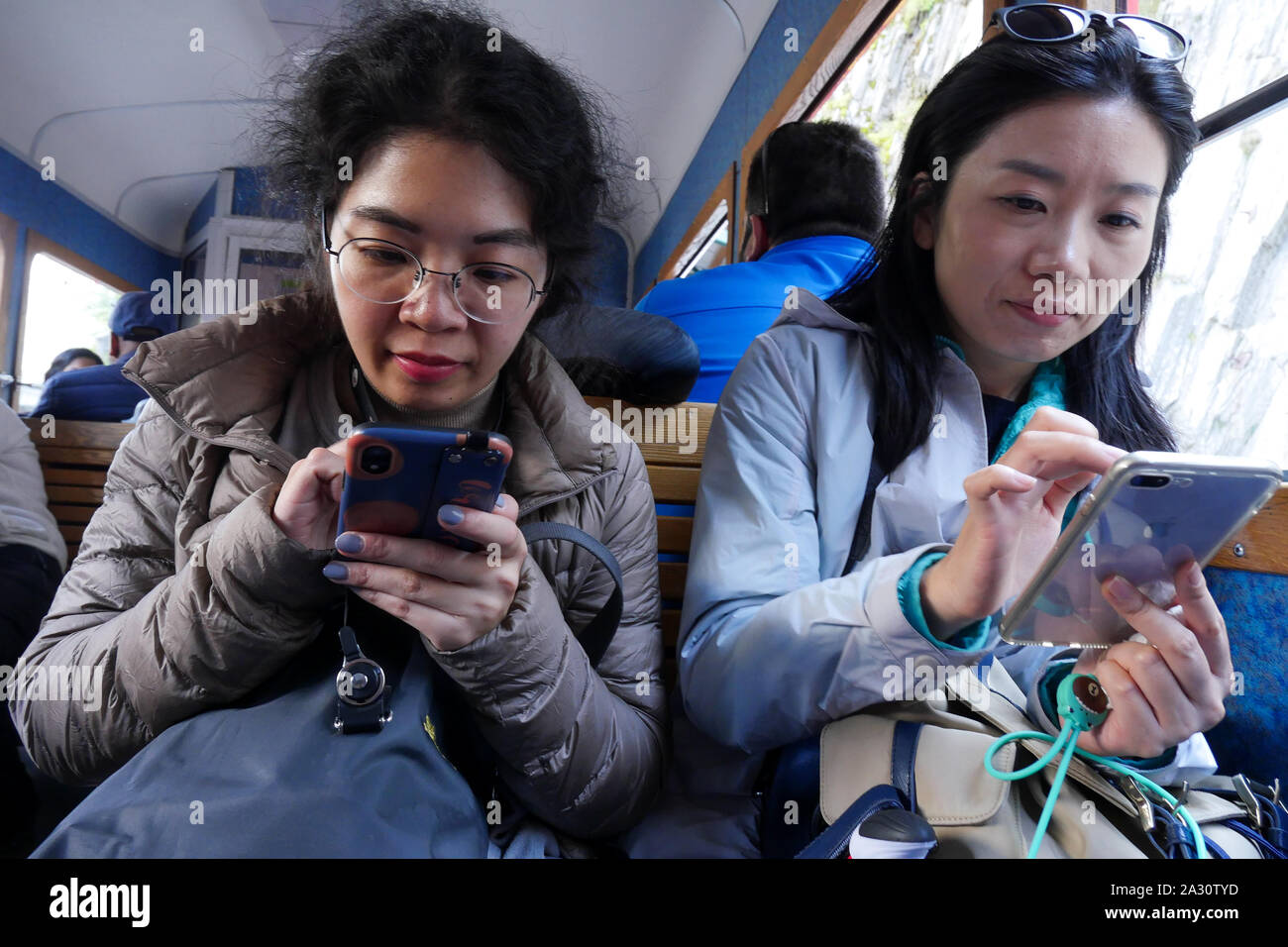 Turisti asiatici tipo notizie sul loro telefono cellulare, Chamonix-Mont-Blanc, Alta Savoia, Francia Foto Stock