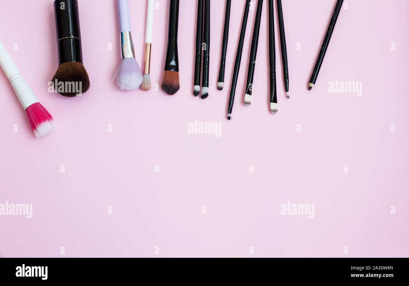 Pennelli per il trucco e prodotti cosmetici su un sfondo rosa Foto Stock